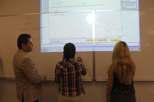 Professor and students solving equations on white board