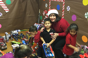 Texas Southmost College Vice President of Instruction, Dr. Marti Flores, distributes toys to Reynaldo Longoria Elementary School students on Dec. 16, 2015, that were collected during TSCâ€™s Third Annual Angel Tree Toy Drive.