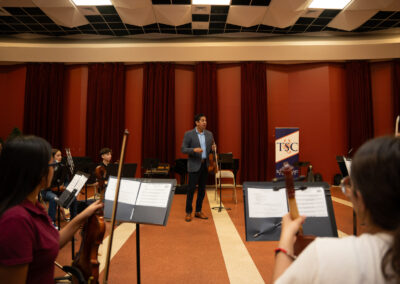 Master Class Conductor Adrian Vaca, a member of Mariachi Sol de Mexico de Jose Hernandez, guides student violinists in a lesson as part of the Mariachi Summer Camp, held at the TSC Performing Arts Center.