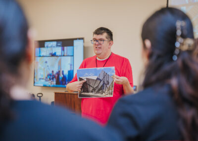 Albert Cadarco, Chair of Planning & Activities Committee with NOMA of Central Texas, goes over details of an architectural rendering with students in the Project Pipeline Summer Architecture Camp.