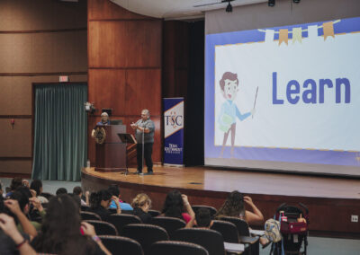 An instructor onstage shows the audience the sign for "learn"