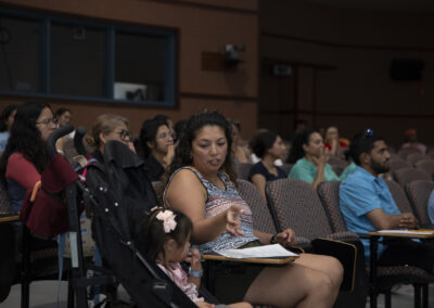 A participant in the audience explains a certain sign to her young daughter.