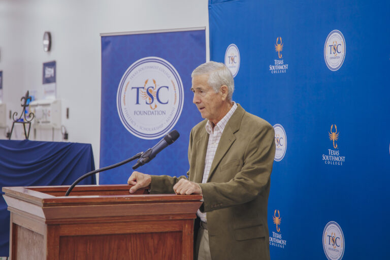 Steven De la Garza delivers a brief speech behind a podium.