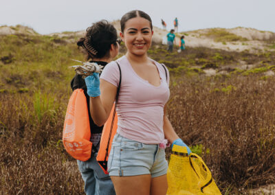 TSC student collects trash along the shoreline at Edwin King Atwood Park during a South Padre Island beach cleanup.