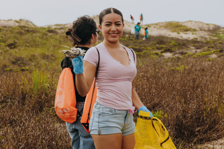 TSC student collects trash along the shoreline at Edwin King Atwood Park during a South Padre Island beach cleanup.