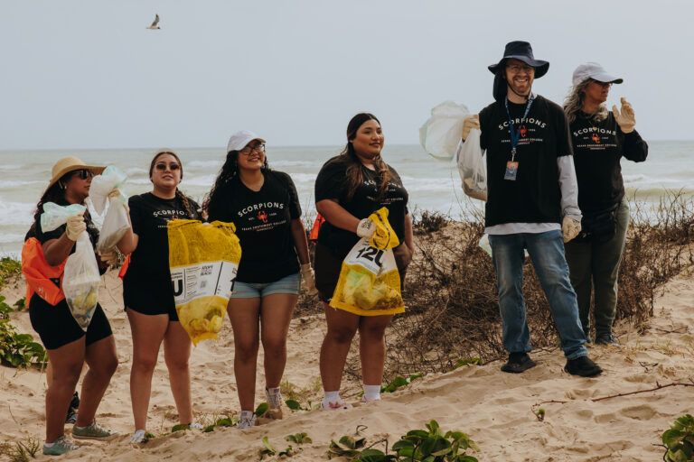 Group photo of Texas Southmost College students participating in a beach cleanup at South Padre Island.